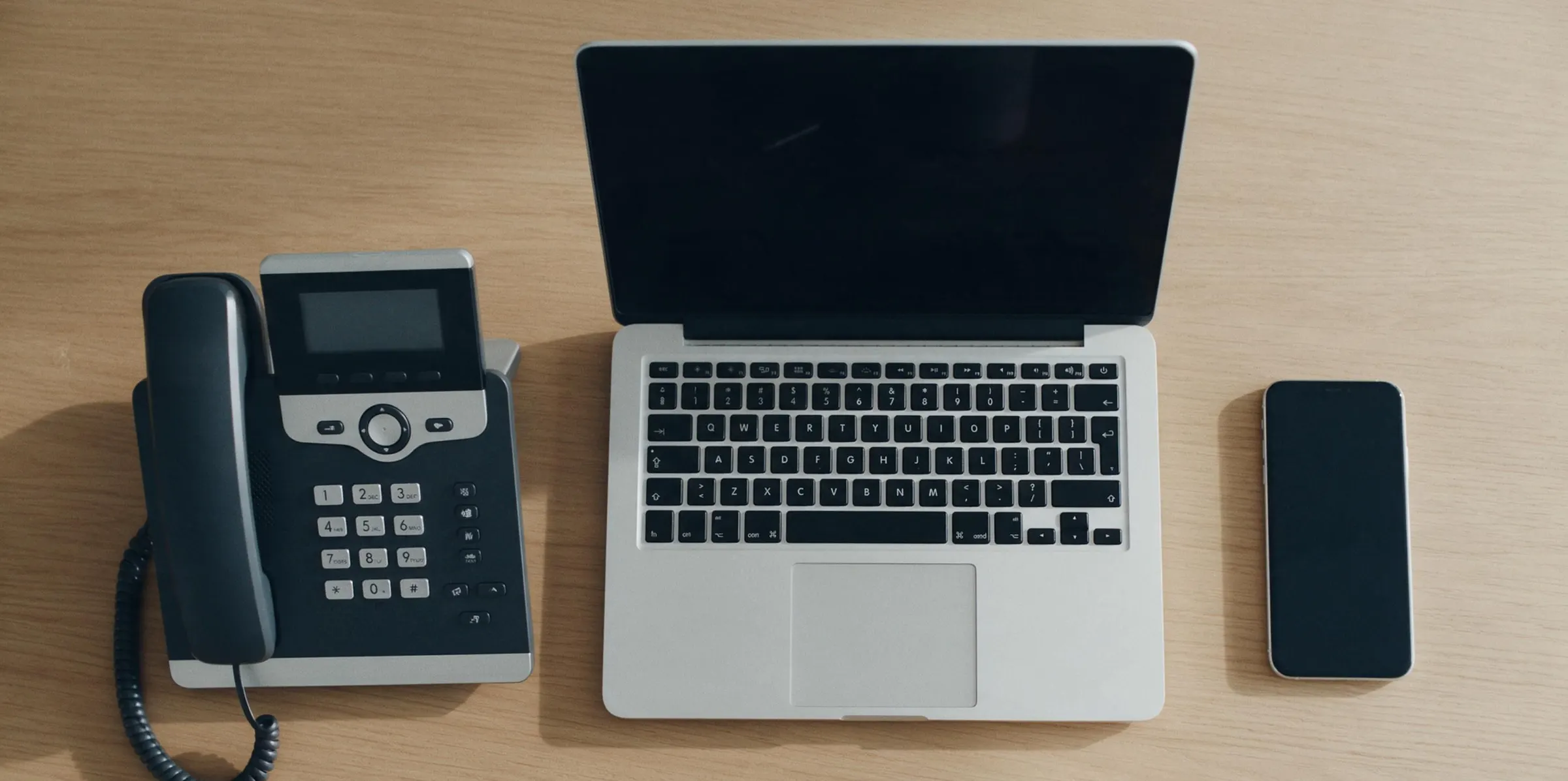 A desk phone, a laptop and a mobile phone side by side on one desk, each showing QuorumVoice.